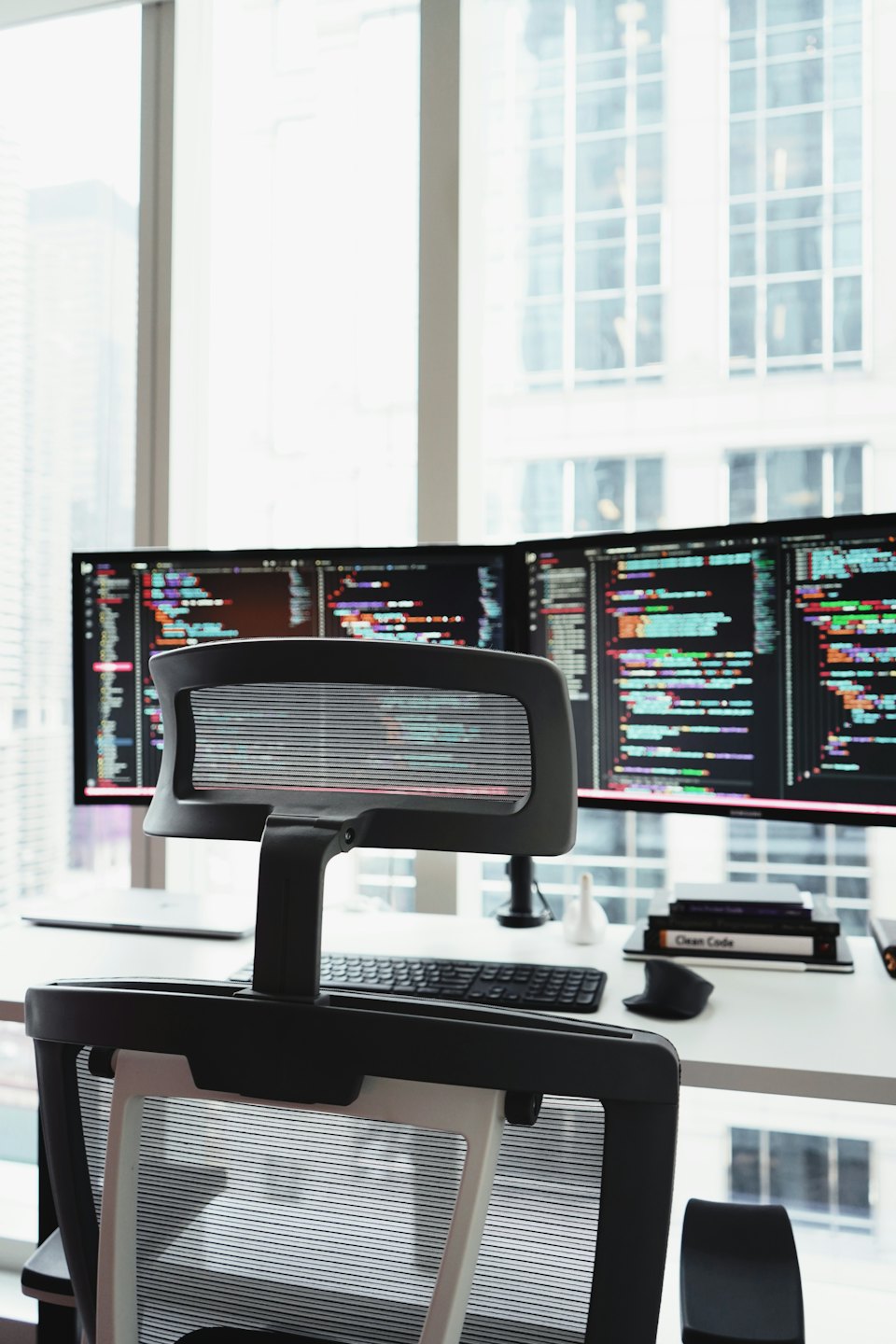 Due monitor di computer con codice su una scrivania bianca.